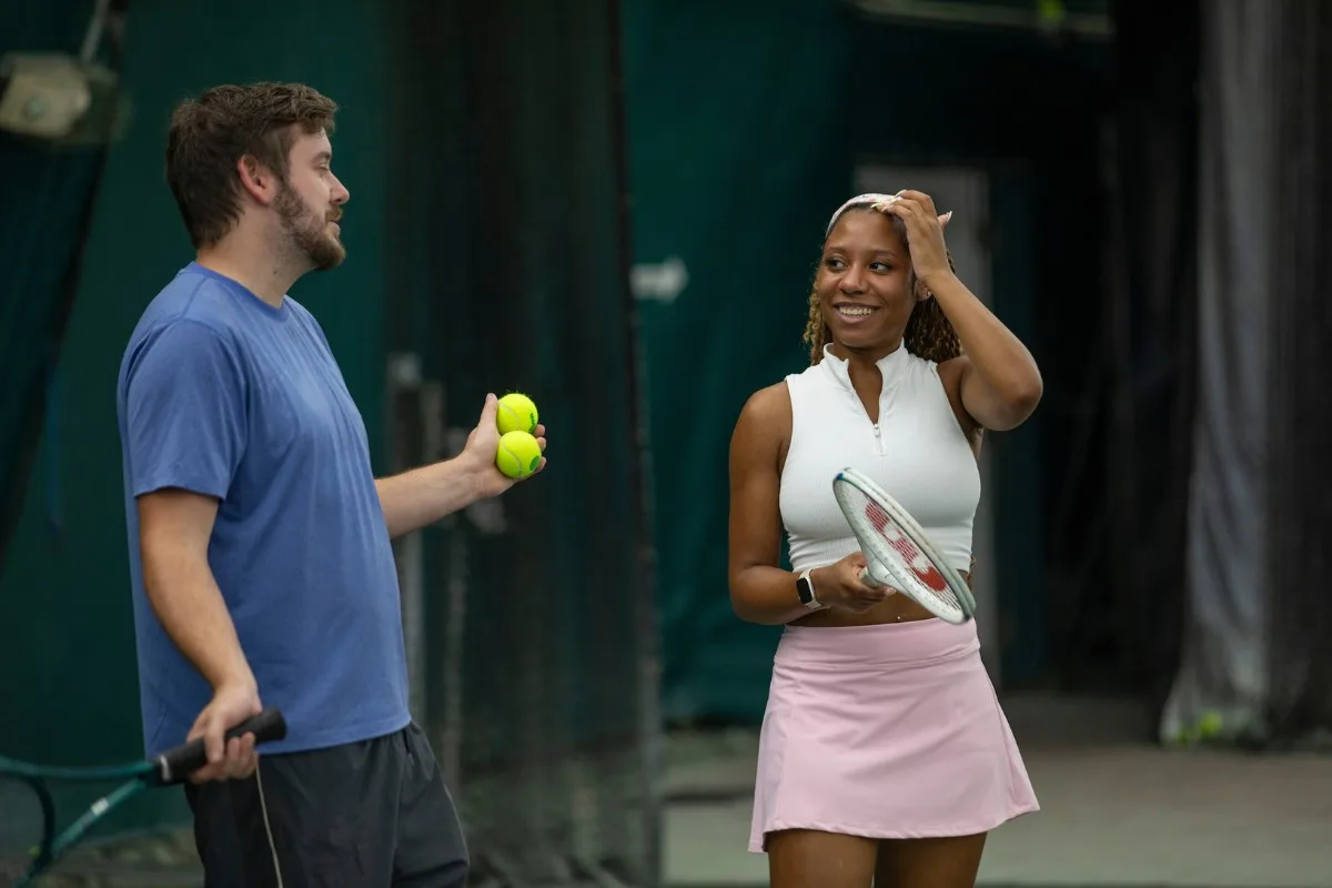Coach instructing adult students at the net on an indoor court at USTA Midwest Tennis Center in Indianapolis