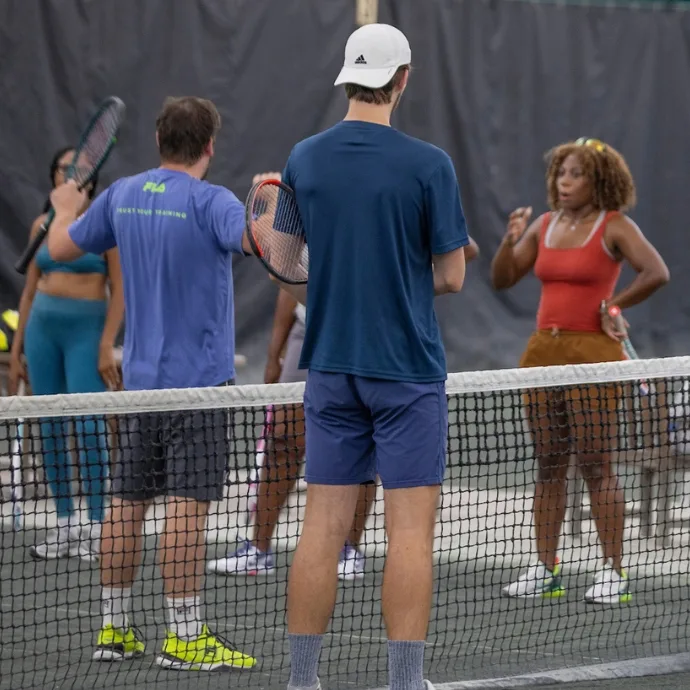 Coach instructing adult students at the net on an indoor court at USTA Midwest Tennis Center in Indianapolis